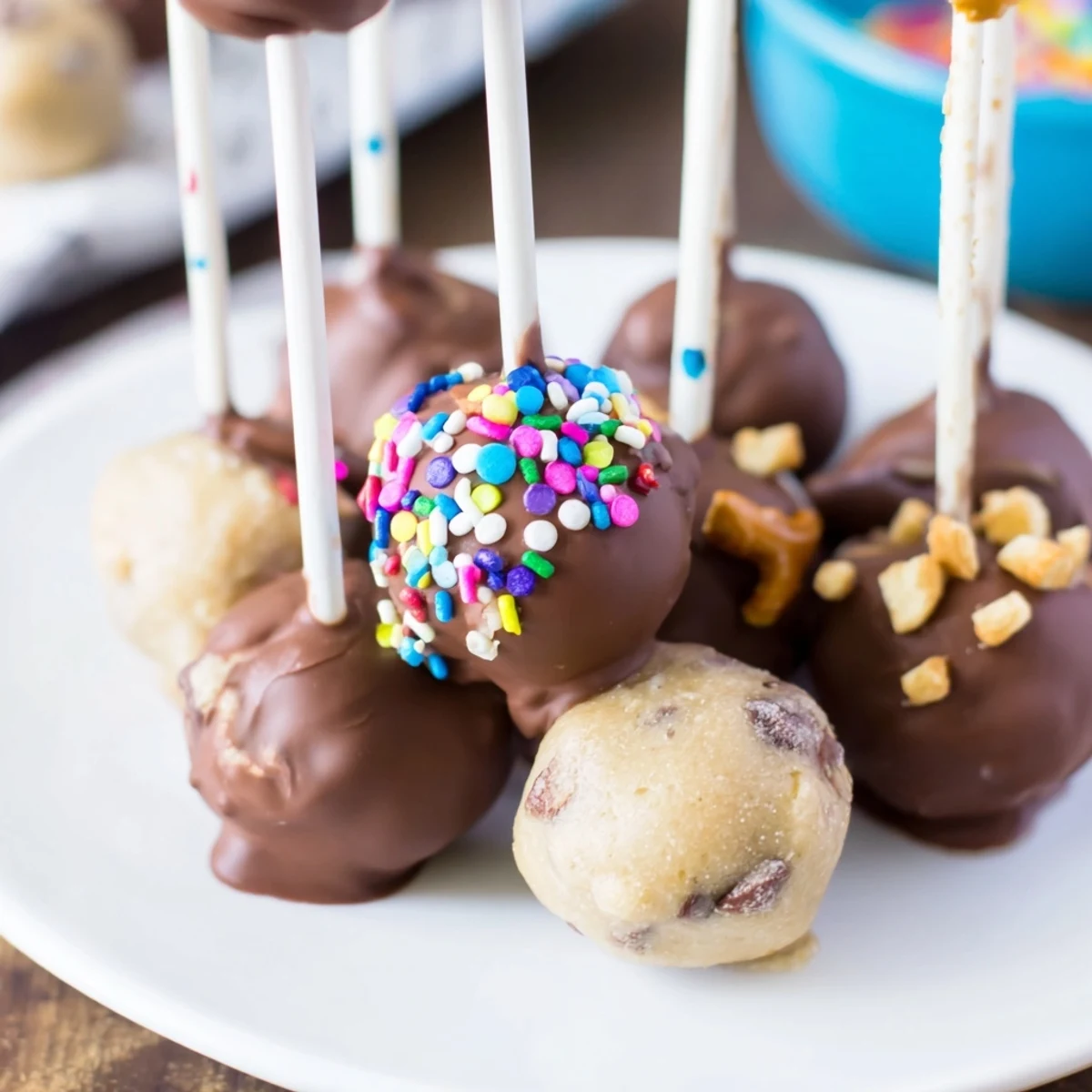 Irresistible Charcuterie Board Cookie Dough Pops drizzled in chocolate with festive sprinkles.  