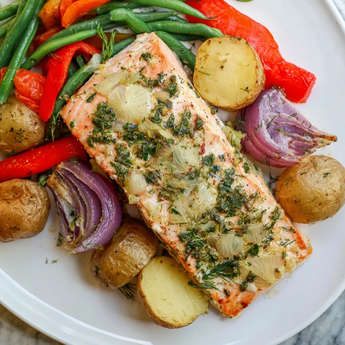 Enjoy a close-up view of flavorful Lemon Herb Salmon & Potato, glistening with herbs and olive oil.