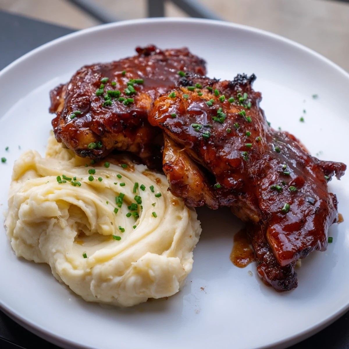 Oven-baked honey BBQ Chicken Thighs with tender meat and a vibrant, flavorful sauce served alongside fluffy mashed potatoes.