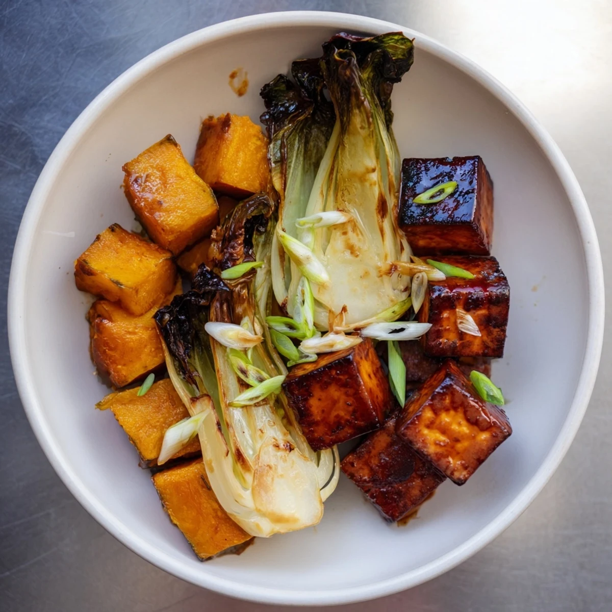 Golden-brown miso-glazed tofu and squash with vibrant bok choy, a delicious vegan dish.