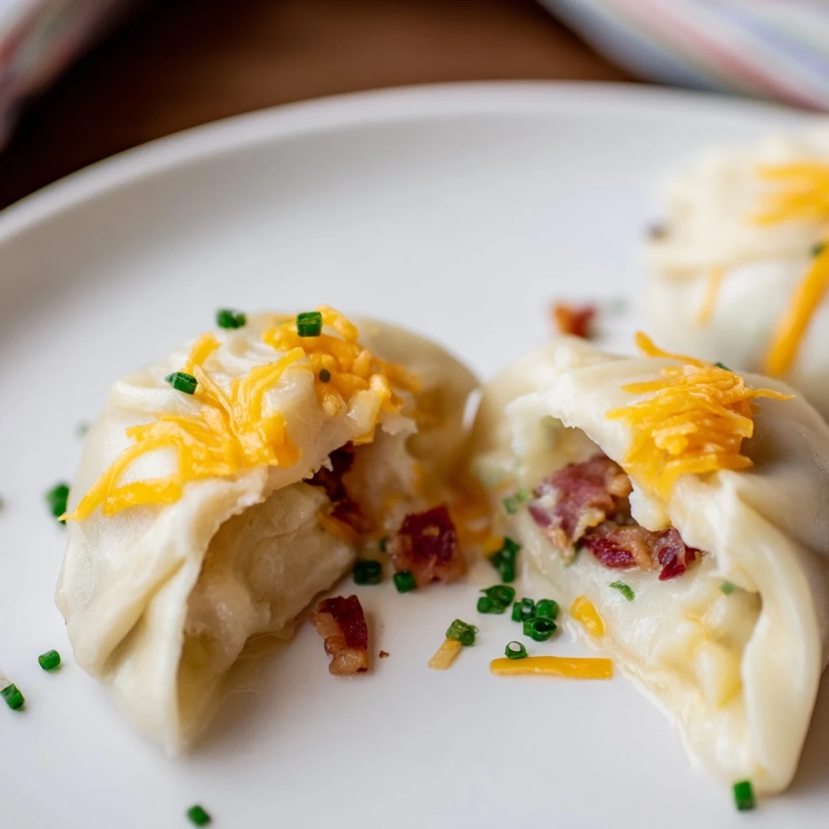 Steaming Loaded Baked Potato Soup Dumplings, showcasing a warm, comforting scene with sprinkled chives and cheese.