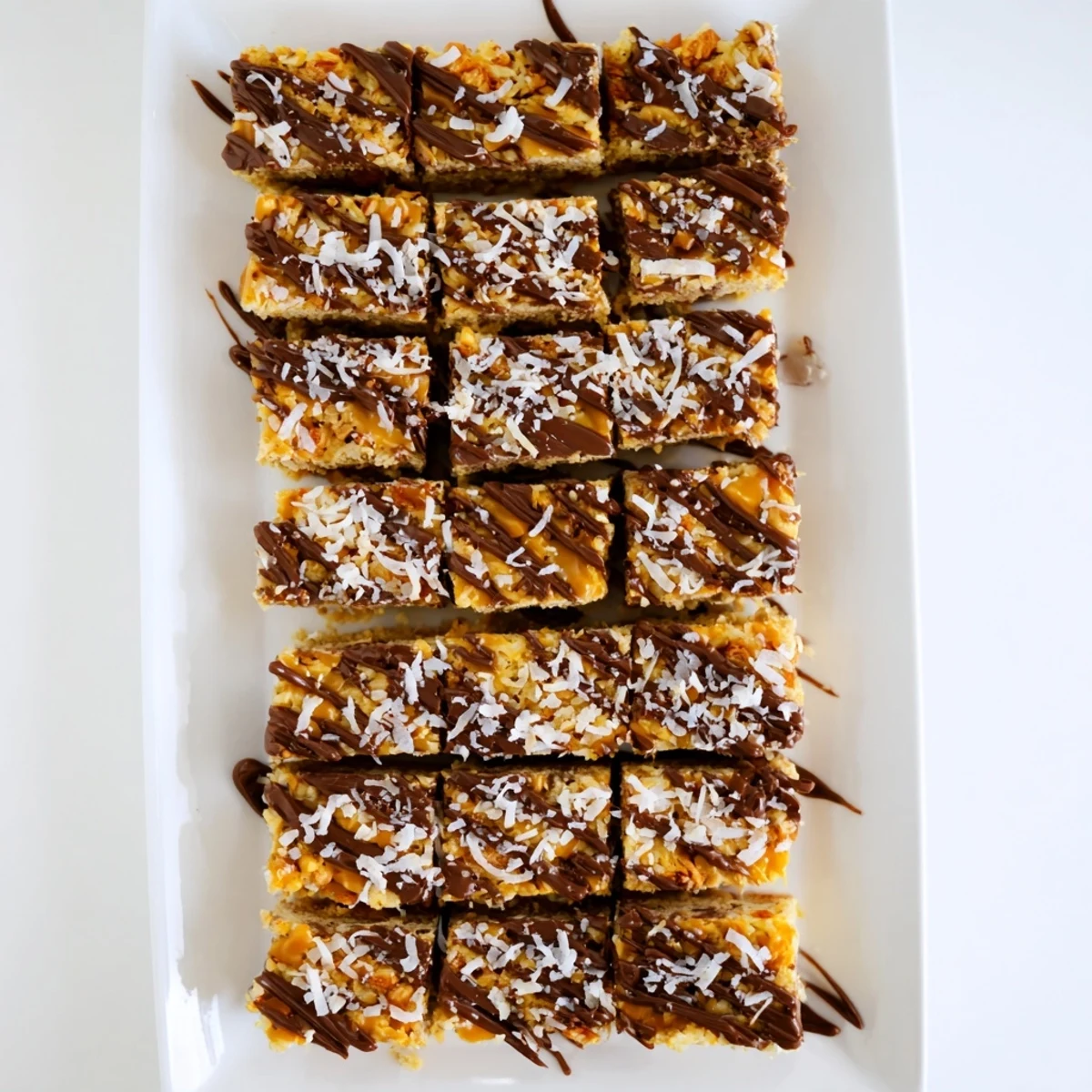 A close-up of delicious 7-Layer Magic Bars, drizzled with caramel and sea salt, ready to enjoy.