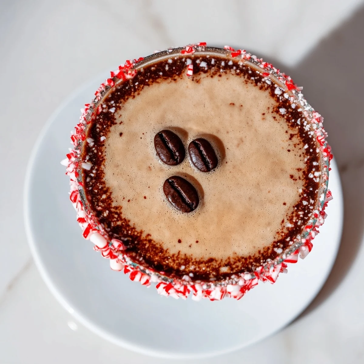 A decadent Peppermint Espresso Martini, garnished with espresso beans on a festive holiday rim.