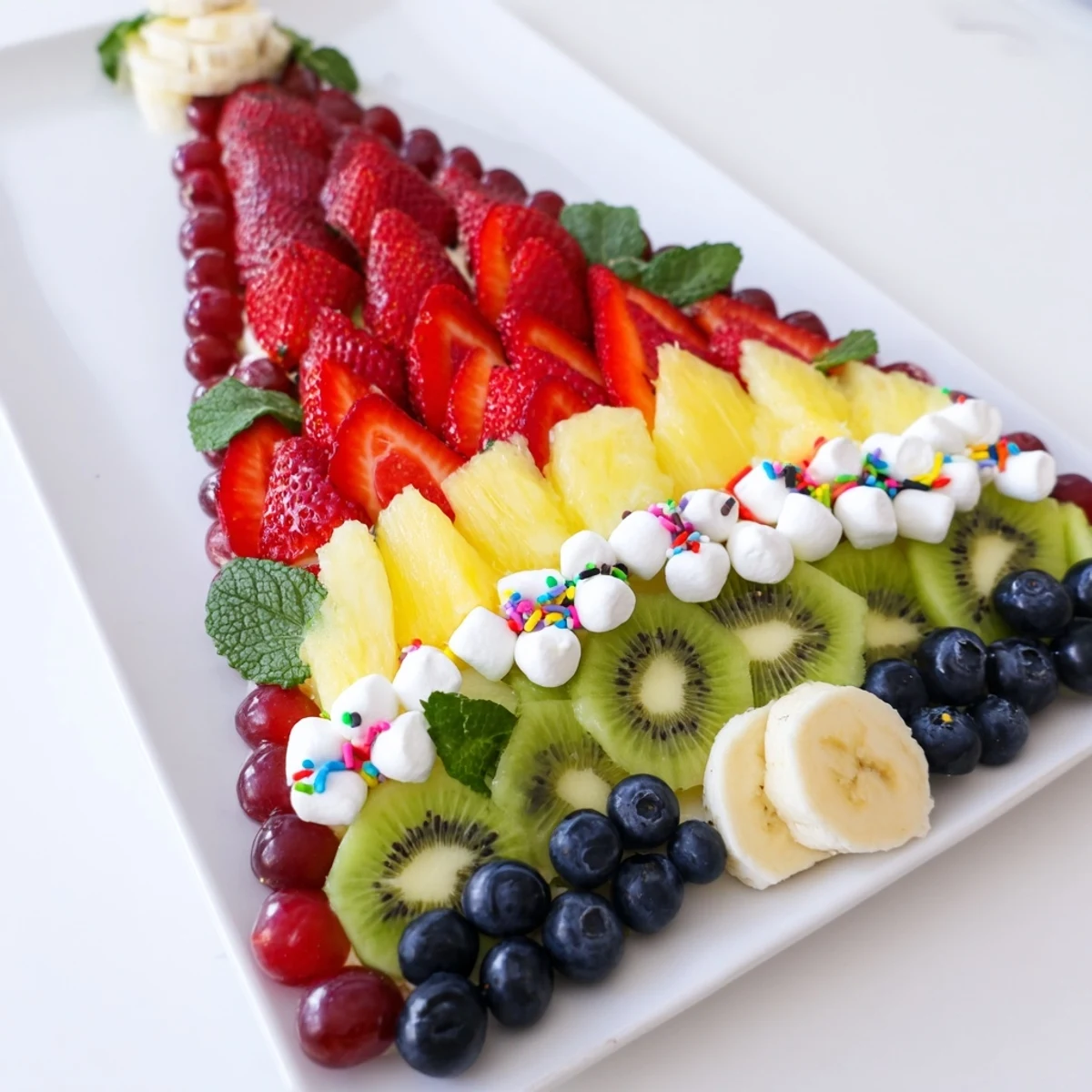 Vibrant Happy Birthday Cake Slice Fruit Board with colorful fruit and marshmallow "frosting."