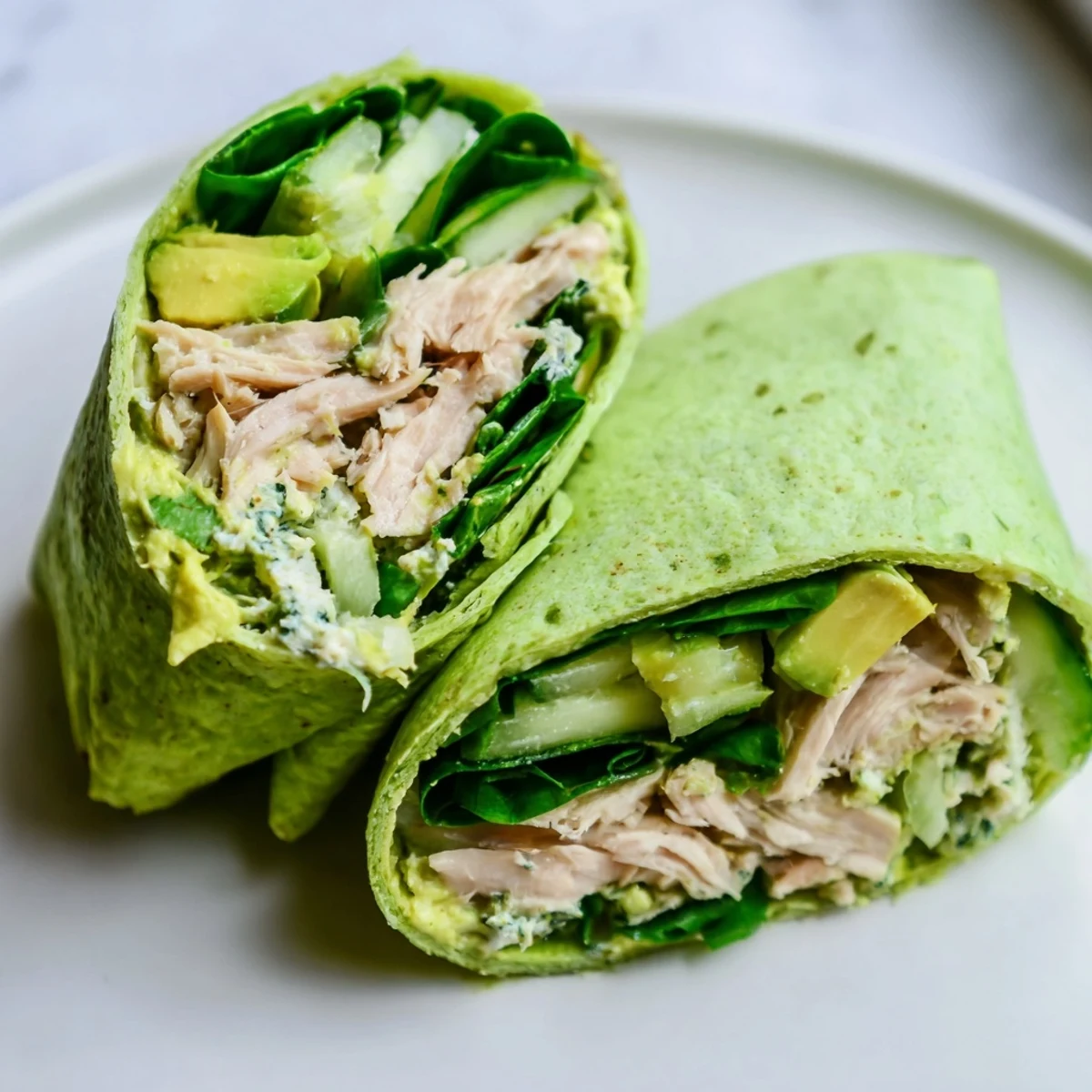 Green Goddess Wellness Wrap, bursting with fresh veggies and chicken, served cut, ready to eat.