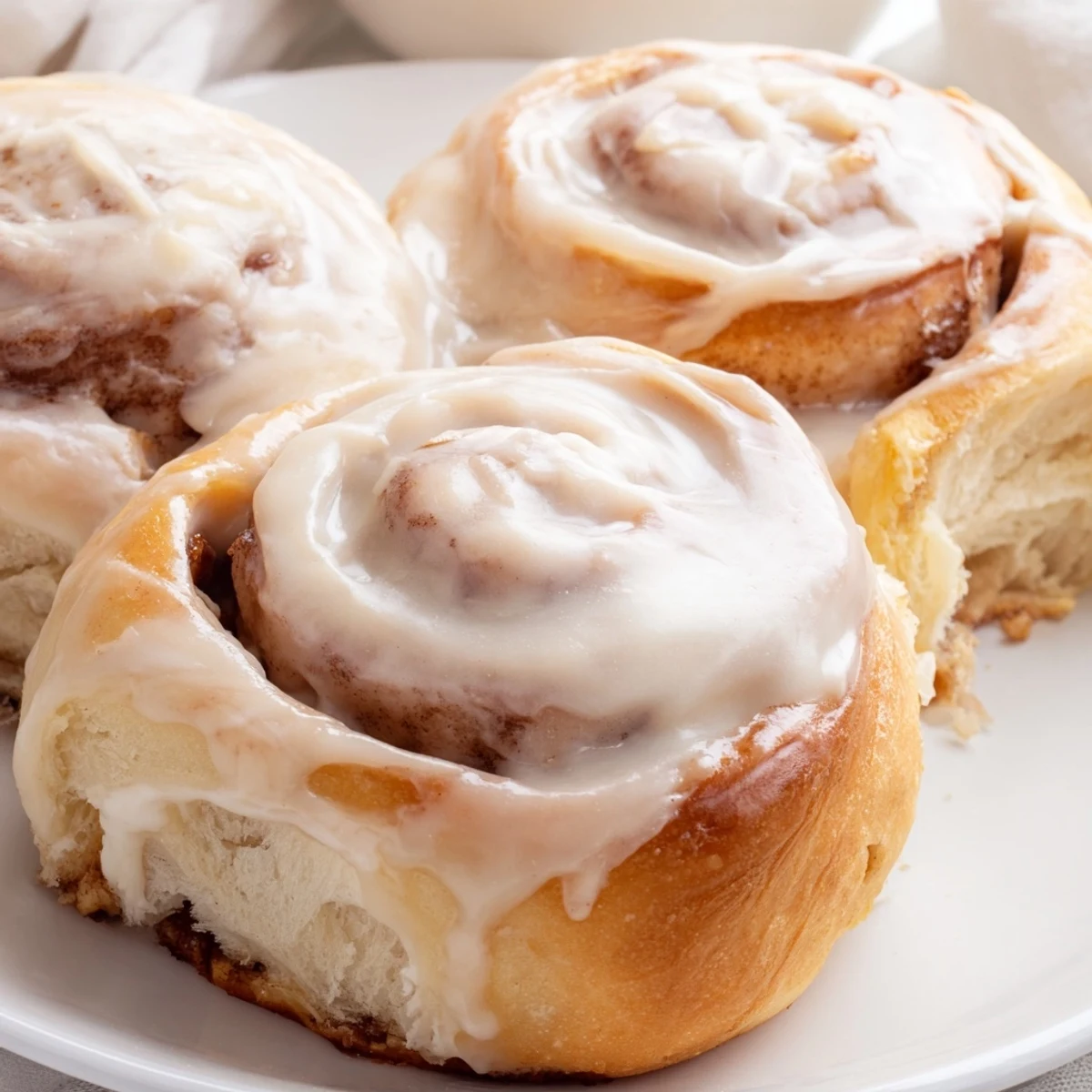Warm, golden Pillow Soft Cinnamon Rolls fresh from the oven, drizzled generously with creamy glaze.