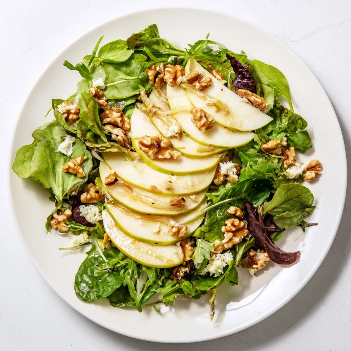 Freshly sliced apples and toasted walnuts tossed in a tangy vinaigrette, served over mixed greens for a crisp winter salad.  