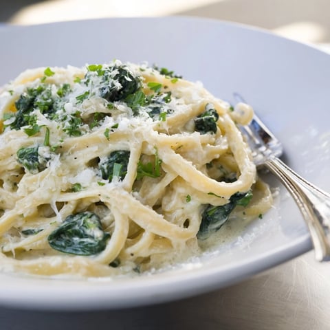 Steaming Creamy Greek Yogurt Spinach Alfredo Pasta, glistening with Parmesan and ready to serve.