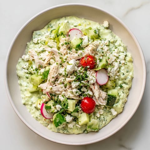 Green Goddess Chicken Nacho Dip, creamy and flavorful, garnished with fresh herbs and served with chips.