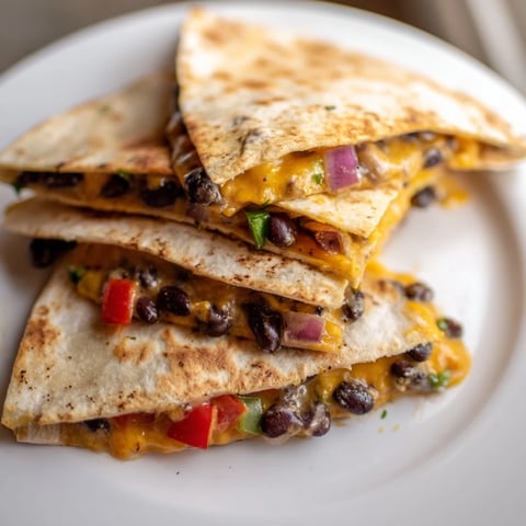 Golden-brown, cheesy Black Bean Quesadilla, filled with savory beans and colorful peppers, ready to eat.