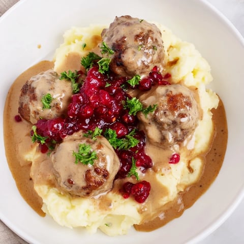 Golden-brown Swedish Meatballs swimming in a creamy, savory sauce, ready to serve with mashed potatoes.