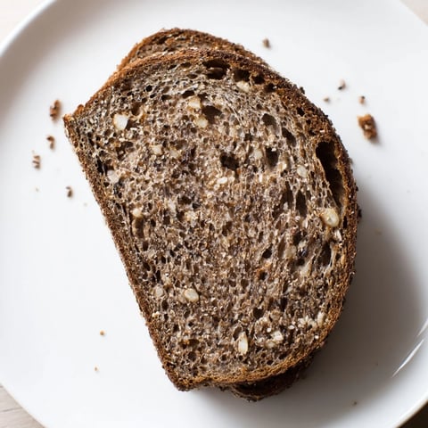 A rustic loaf of Estonian Leib sourdough, featuring a dark, crackly crust and seeded top.