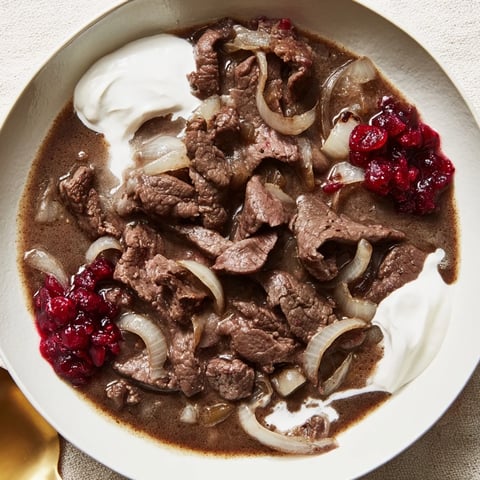 Tender Finnish Reindeer Stew, served with creamy mashed potatoes and vibrant lingonberries.