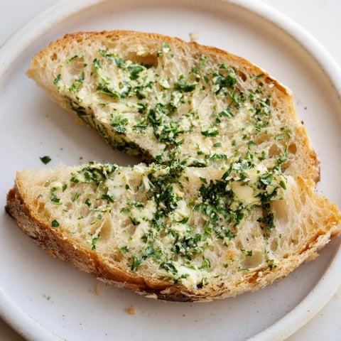 Golden, bubbly herb butter toast served warm, topped with flaky sea salt and fresh herbs.