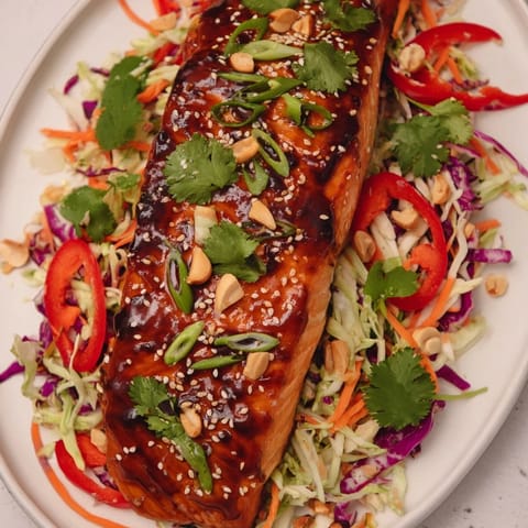 A close-up of teriyaki salmon atop crisp slaw, ready for a healthy and satisfying bowl.