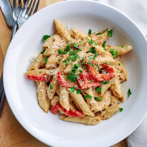 A steaming plate of Creamy Cajun pasta features al dente penne coated in a spicy, velvety sauce with sweet peppers.  