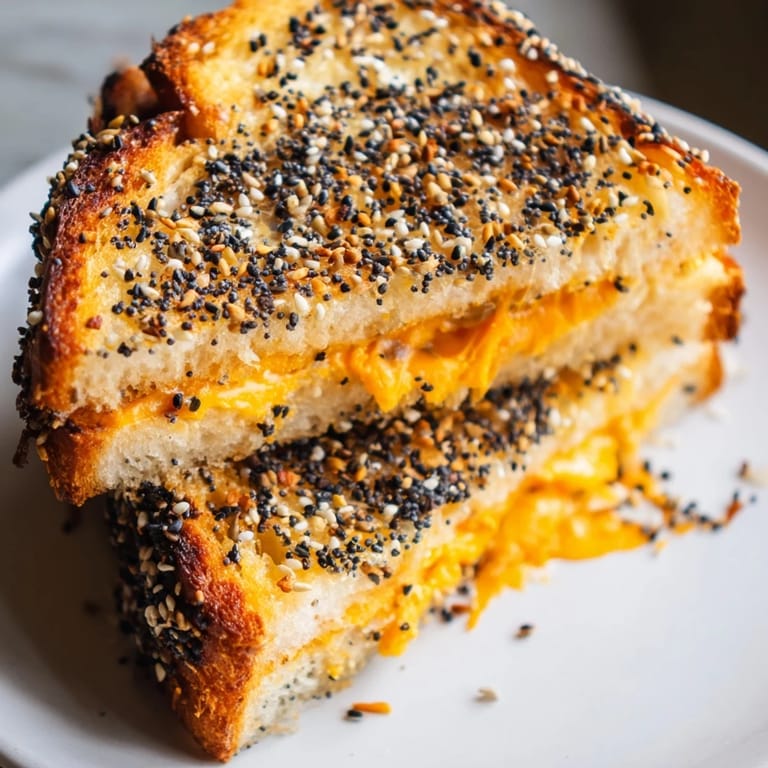 Perfectly grilled Everything Bagel Grilled Cheese served with a side of creamy tomato soup.