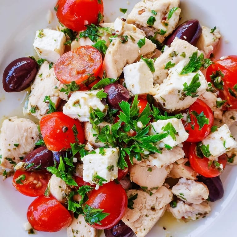 A close-up of Mediterranean Chickpea Chicken Salad highlights crisp cucumbers, briny Kalamata olives, and tender chickpeas mixed with parsley.  