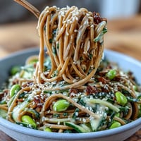 Sesame Ginger Noodle Bowl with fresh cucumber, carrots, and edamame, drizzled in a creamy sesame-ginger dressing for a refreshing meal.  