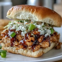 Crockpot Mississippi Chicken Sliders with Coleslaw on a platter, juicy slow-cooked chicken topped with crisp, tangy slaw on soft slider buns.