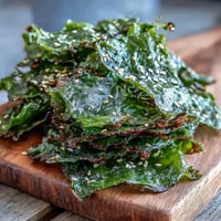 Crispy seaweed snack chips with sesame seeds and sea salt topping a baking sheet.